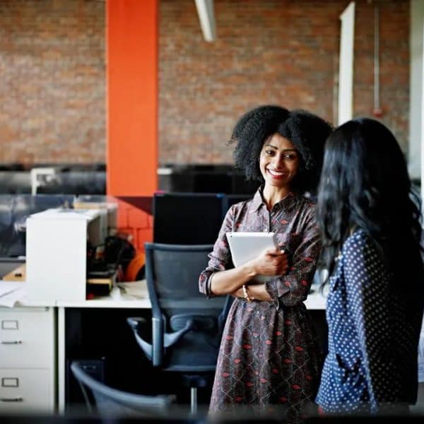 Two women talking and smiling in open plan office